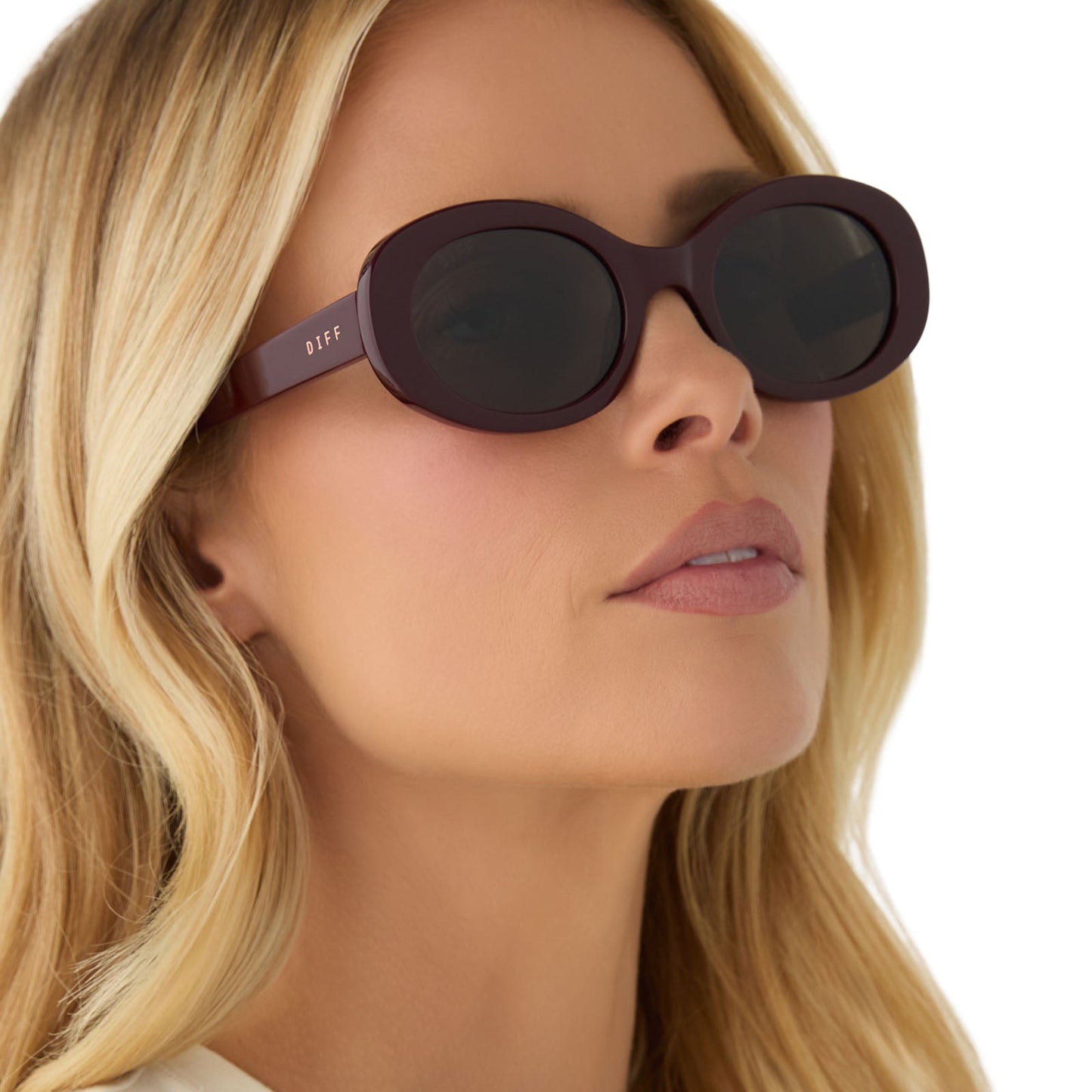 on model - female wearing diff eyewear featuring the lainey oval sunglasses with a dark cherry lacquer frame and grey lenses angled view