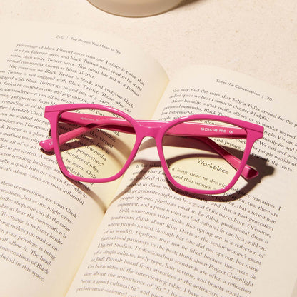 lifestyle - diff eyewear featuring the leah square blue light readers with a peony pink frame laying on an open book