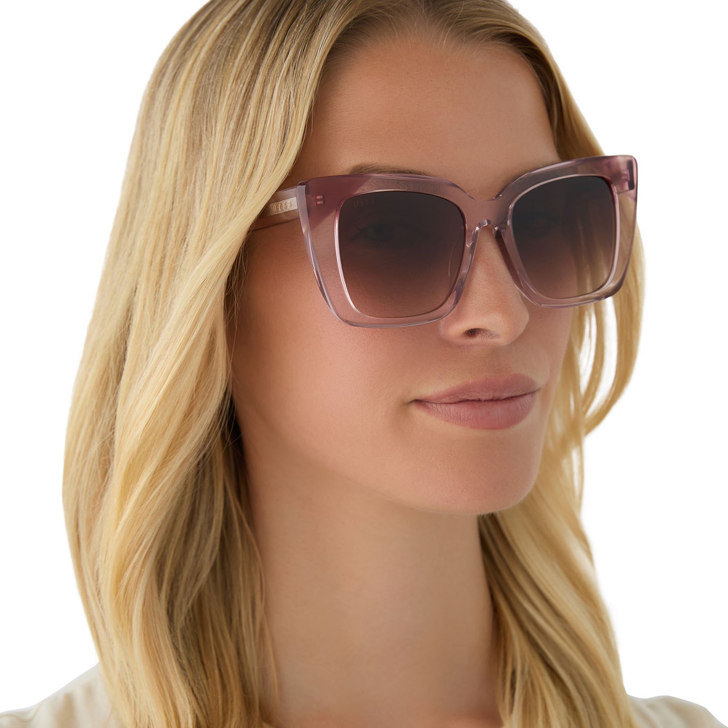 on model - female wearing diff eyewear featuring the lizzy cat eye sunglasses with a light pink crystal + fleur pink tort tips frame and brown gradient lenses angled view