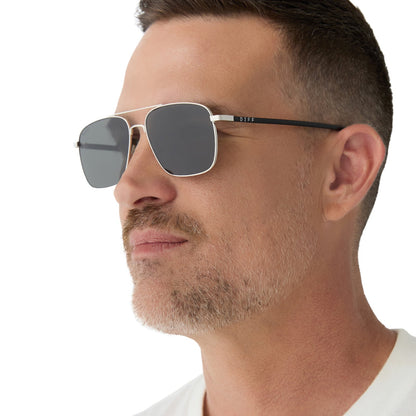 on model - male wearing yellowstone x diff eyewear featuring the rip wheeler navigator sunglasses with a silver frame and grey polarized lenses angled view