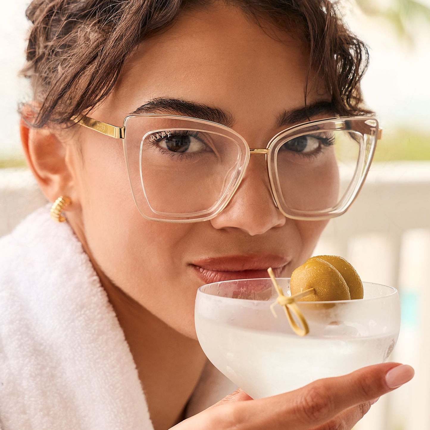 lifestyle - female drinking lemonade wearing diff eyewear featuring the becky iv cat eye prescription glasses with a clear crystal with gold frame front view