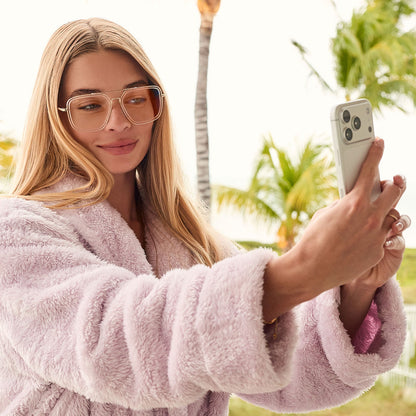 lifestyle - female taking a selfie at the beach diff eyewear featuring the jordan navigator prescription glasses with a gold frame, clear crystal temple tips front view