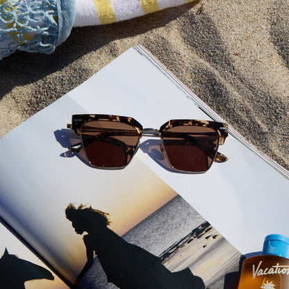 lifestyle - still life of diff eyewear capri tortoise sunglasses laying on a magazine at the beach