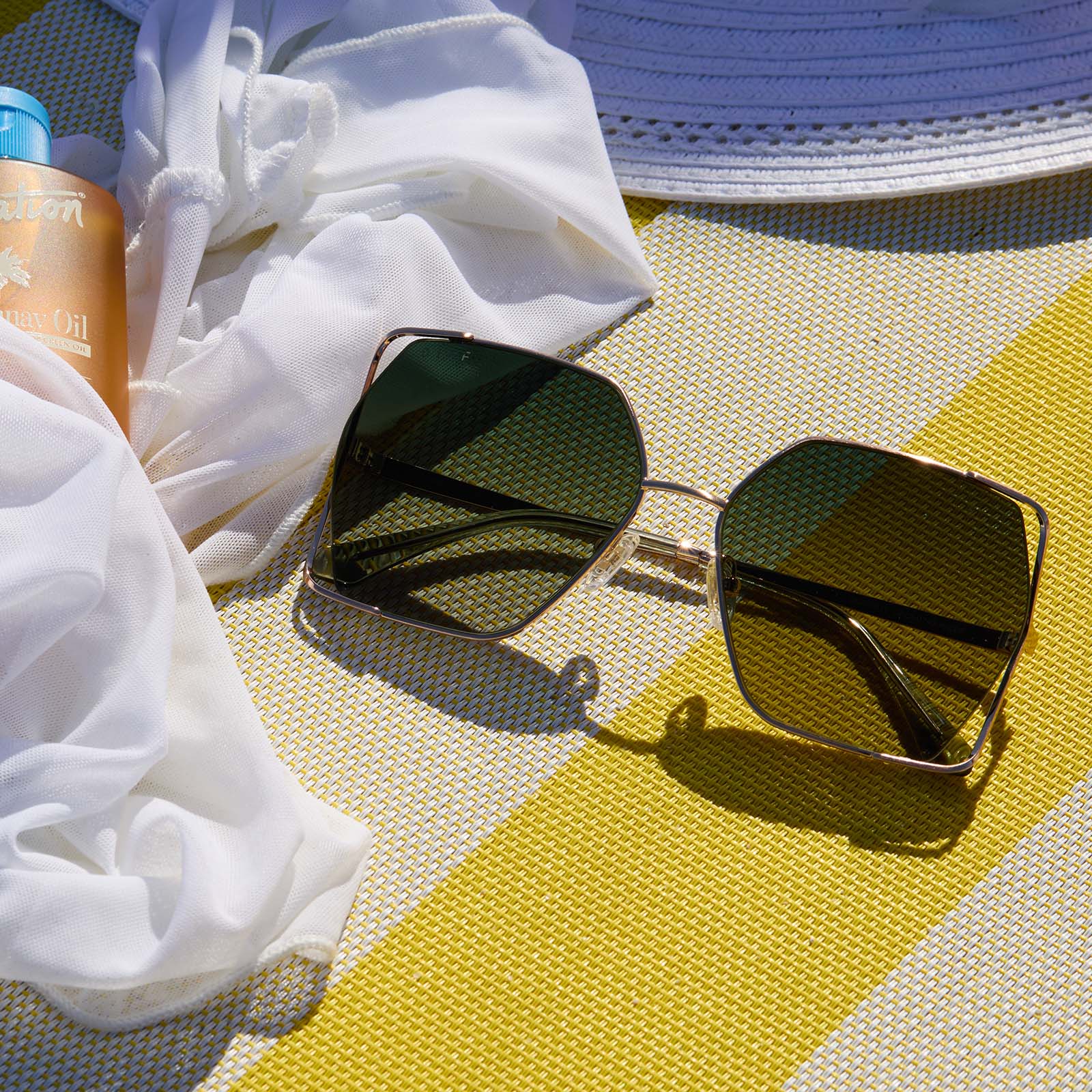 lifestyle - still life of diff eyewear donna iv gold champagne cool matcha sunglasses laying on the beach