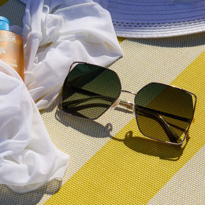 lifestyle - still life of diff eyewear donna iv gold champagne cool matcha sunglasses laying on the beach