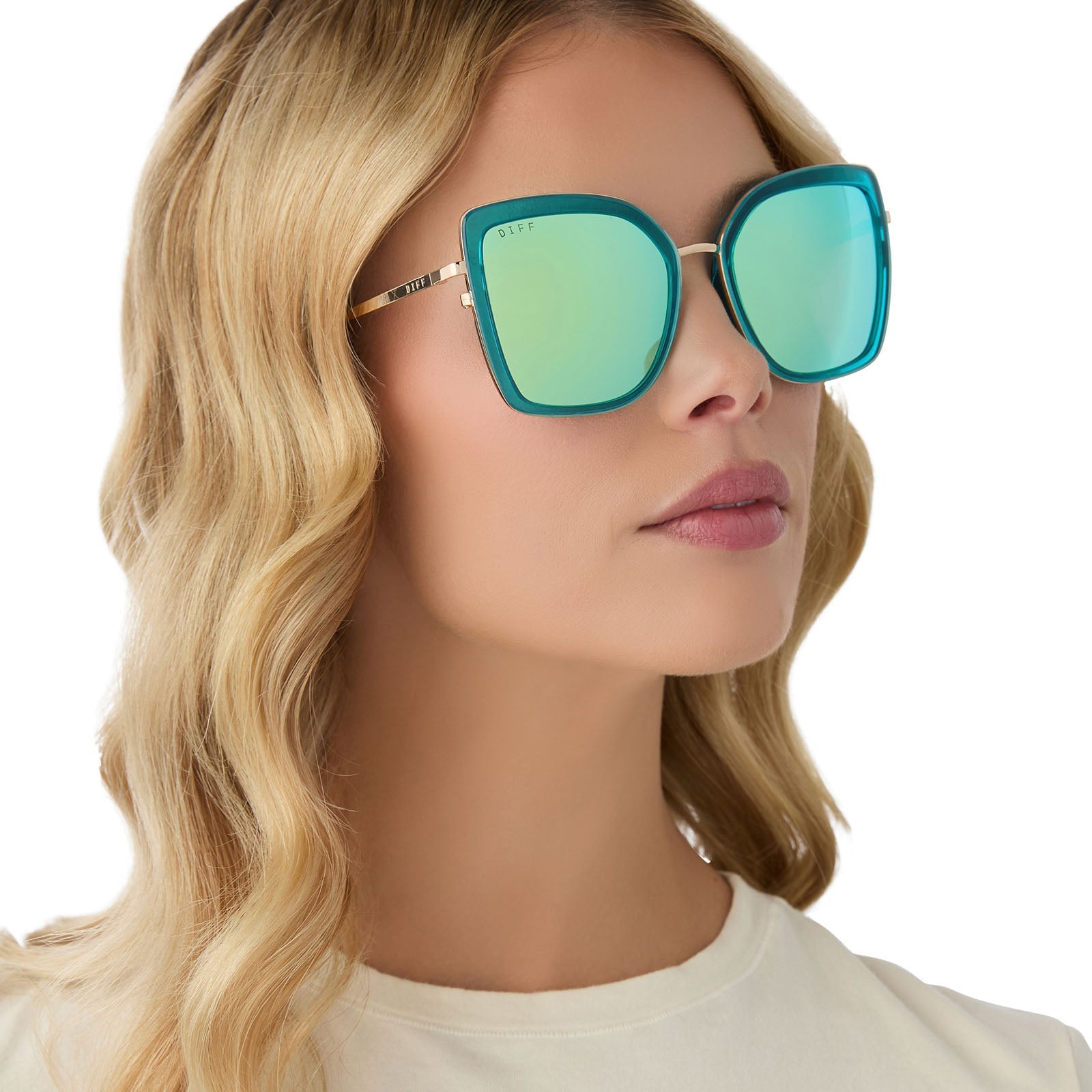 on model - female wearing diff eyewear clarisse cat eye sunglasses with a turquoise ice crystal blue frame and gold metal legs and turquoise ice mirror lenses angled view