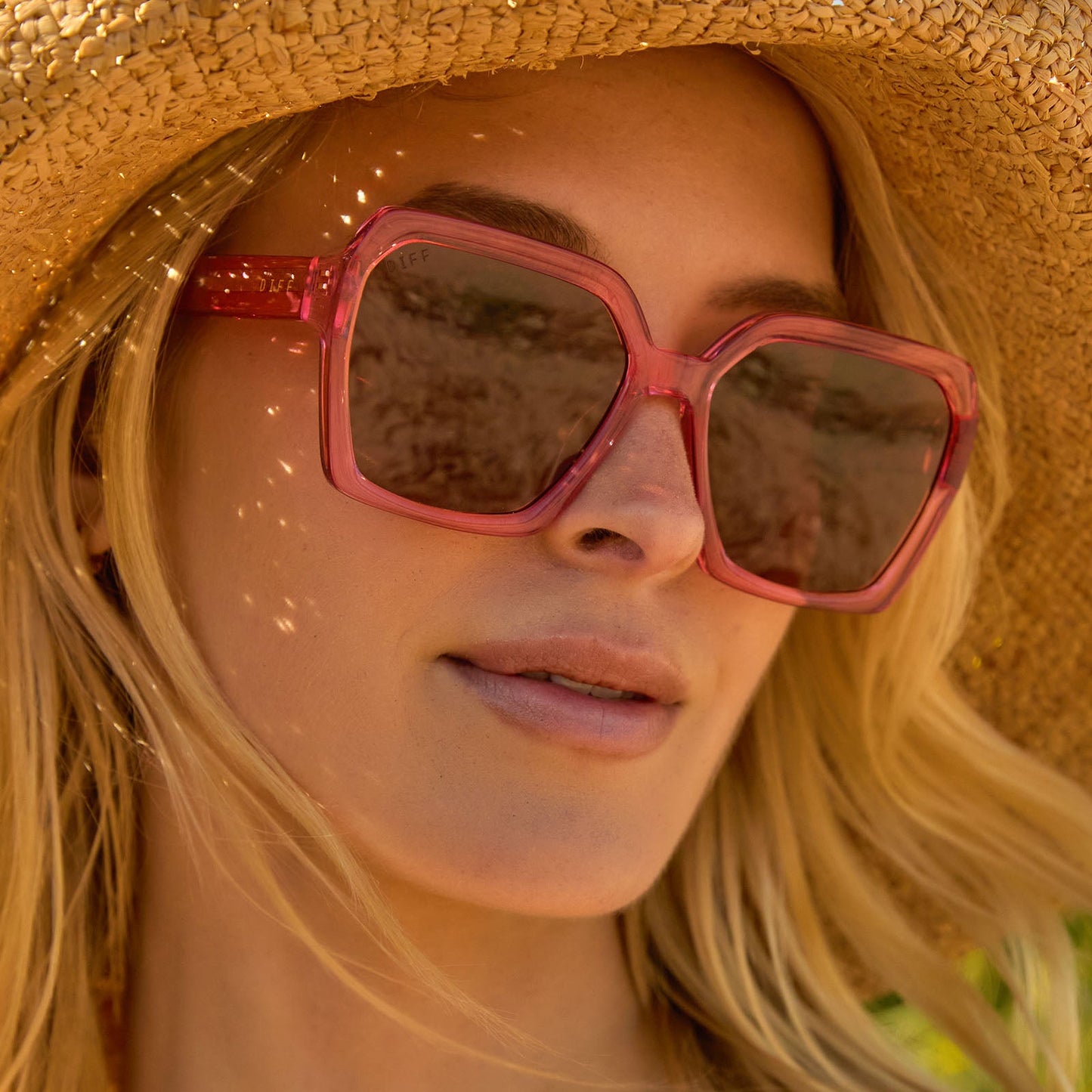 lifestyle - female wearing diff eyewear sloane square oversized sunglasses with a candy pink crystal acetate frame and brown lenses front view