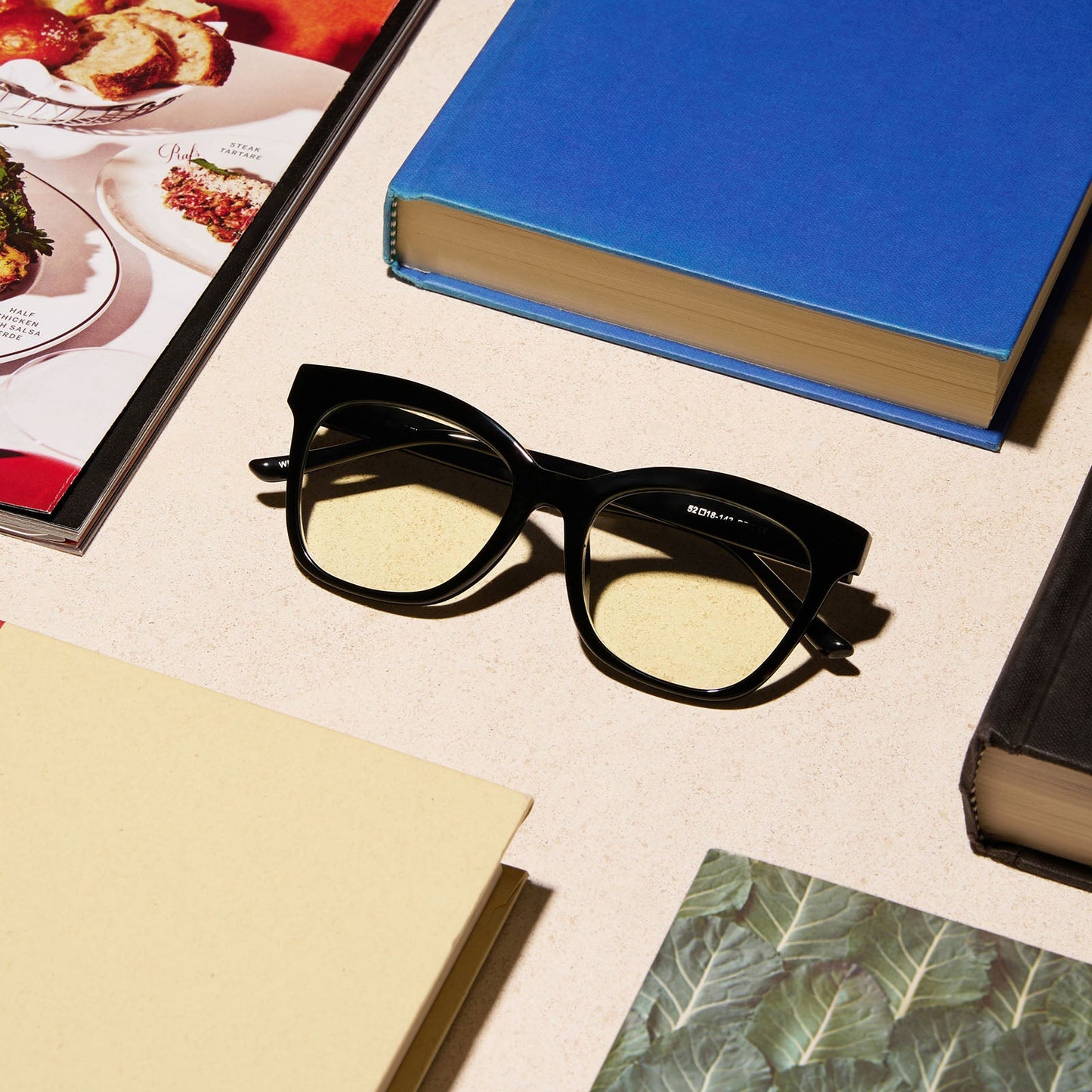 lifestyle - diff eyewear featuring the willa square blue light readers with a black frame on a desk