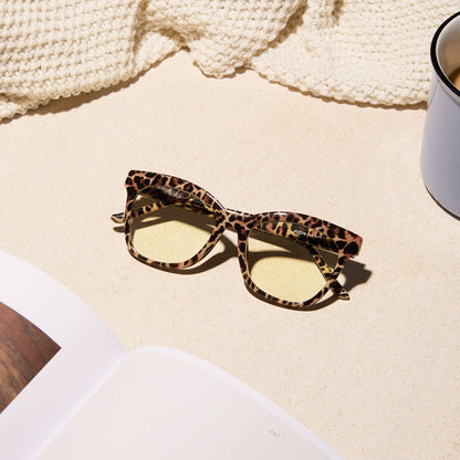 lifestyle - diff eyewear featuring the willa square blue light readers with a leopard tortoise frame laying on a desk