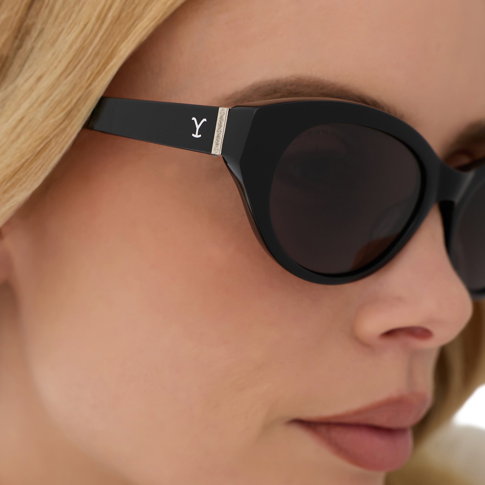 on model - blonde female wearing yellowstone x diff eyewear featuring the teeter round sunglasses with a classic black acetate frame and grey polarized lenses detailed view
