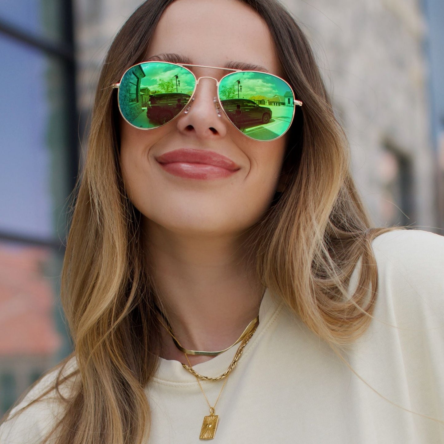 lifestyle - female outside wearing diff eyewear cruz gold and green mirror polarized sunglasses angled view