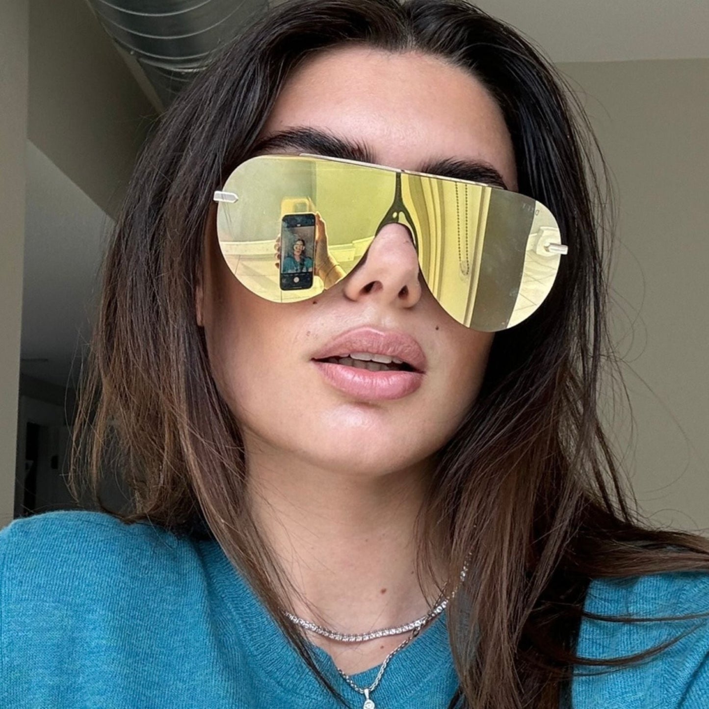 customer content - brunette wearing imani shield gold sunglasses with blue tee